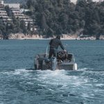 A man standing and steering a motorboat on the Adriatic Sea near Budva, Montenegro's coastline.