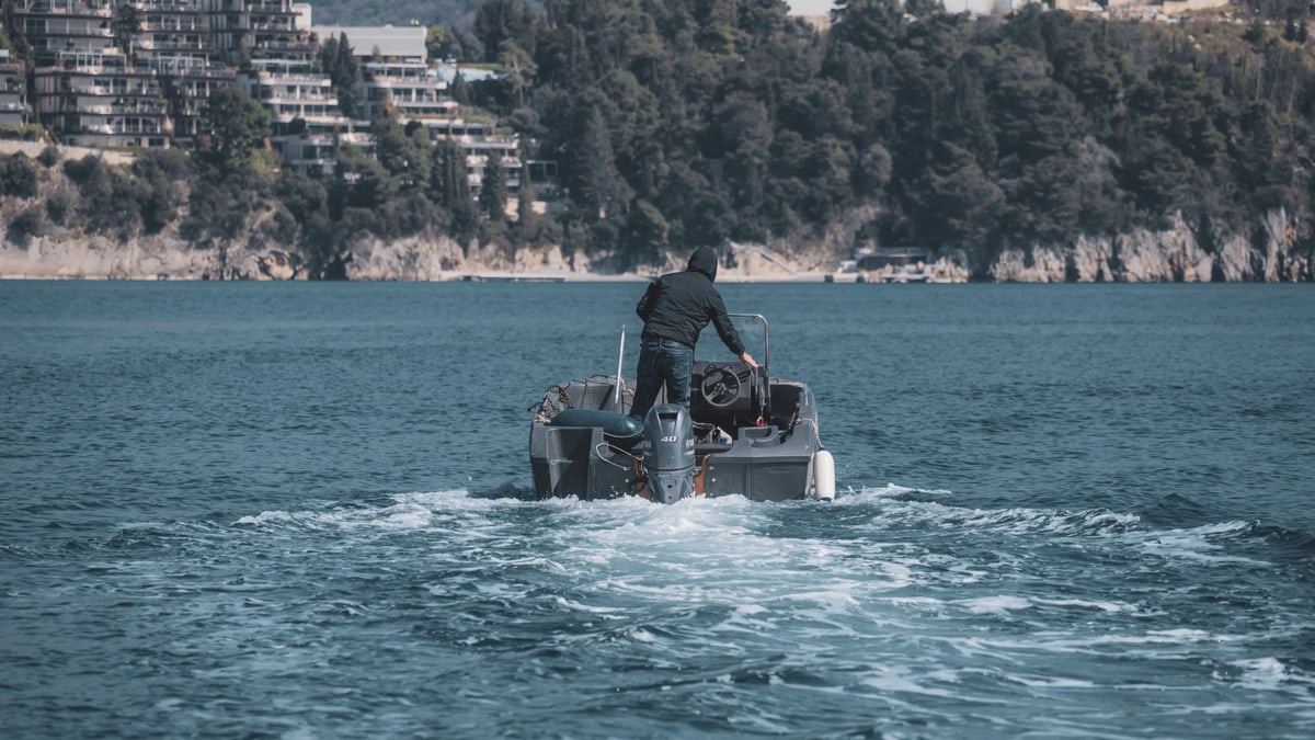 A man standing and steering a motorboat on the Adriatic Sea near Budva, Montenegro's coastline.